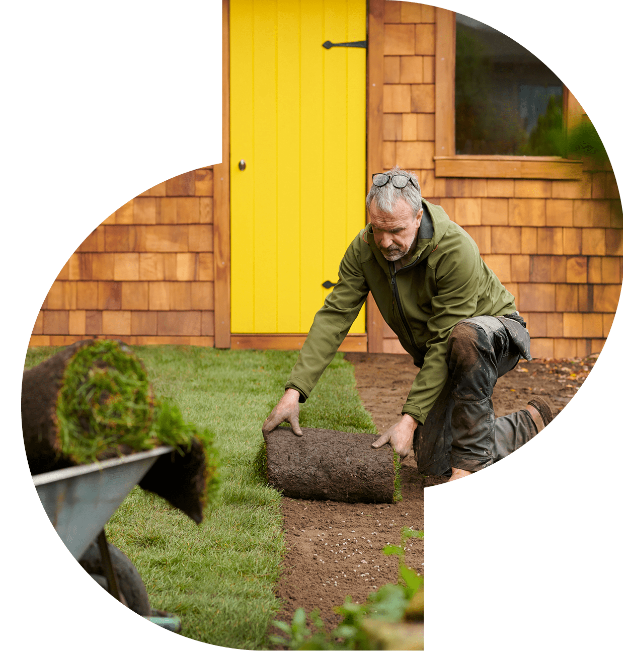 Man laying sod in garden area.